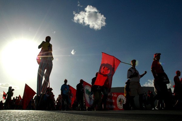 Trabalhadores Sem Terra empunhando bandeiras
